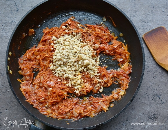 В сковороде разогреваю растительное масло, перекладываю овощи и тушу 2–3 минуты. Добавляю томатную пасту и немного говяжьего бульона, перемешиваю и тушу овощную смесь еще 2–3 минуты. Добавляю хмели-сунели, аджику, рубленые грецкие орехи и измельченный чеснок, перемешиваю.