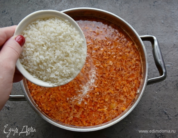 Пассерованные овощи добавляю в бульон и варю на медленном огне 5 минут. Всыпаю круглозерный рис, соль, перемешиваю. После закипания даю супу покипеть минут пять, накрываю кастрюлю крышкой и отключаю огонь. Оставляю суп на 20 минут, чтобы рис дошел до готовности.