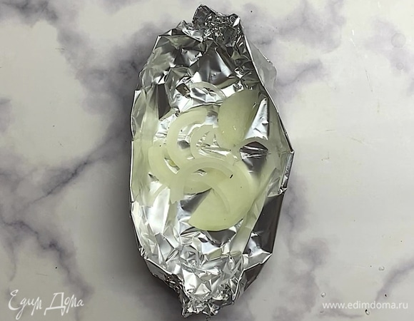 Из фольги формируем лодочки. Вниз выкладываем лук, сверху — стейк форели.