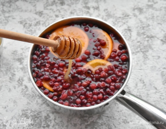 Довожу до кипения на среднем огне и даю покипеть минуты 3–5. После чего накрываю сотейник крышкой и отключаю огонь. Даю напитку настояться минут 5. После чего процеживаю его через сито, раздавливая ягоды клюквы ложкой, чтобы сок из них попал в напиток. Ягодный, апельсиновый жмых, гвоздику и корицу удаляю. Для сладости добавляю в напиток мед. Можно добавить сахар по вкусу. Подаю напиток в теплом виде.