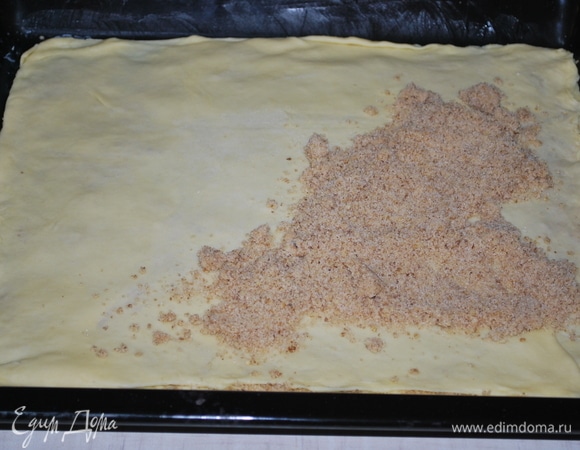 Тесто достаньте из холодильника, разделите на 6–7 равных частей (ориентируйтесть на свой противень, у меня 40х30 см, я тесто разделила на 7 частей по 130 г). Противень смажьте сливочным маслом. Одну часть теста тонко раскатайте по размеру противня. Тесто выложите на противень и посыпьте 1/6 частью начинки из орехов.