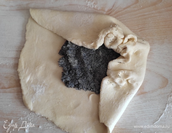 Припылить стол мукой. Тесто раскатать в небольшой круг. На середину выложить начинку и немного распределить по пласту теста. Затем края теста собрать к центру, перемещаясь по кругу.