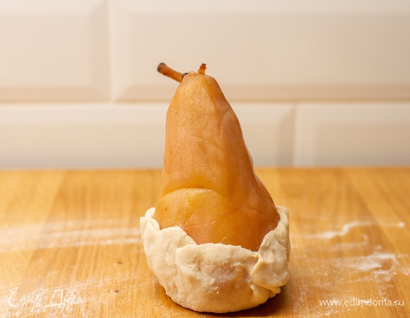 В углубление груши положить кусочки шоколада, поставить грушу на круг теста и завернуть, как показано на фото.