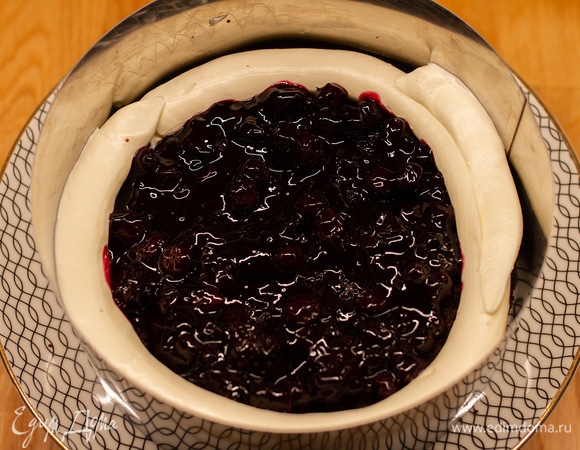 Сделать по краю бисквита бортик из крема. Выложить половину черничного соуса. Добавить еще крема сверху и разровнять.