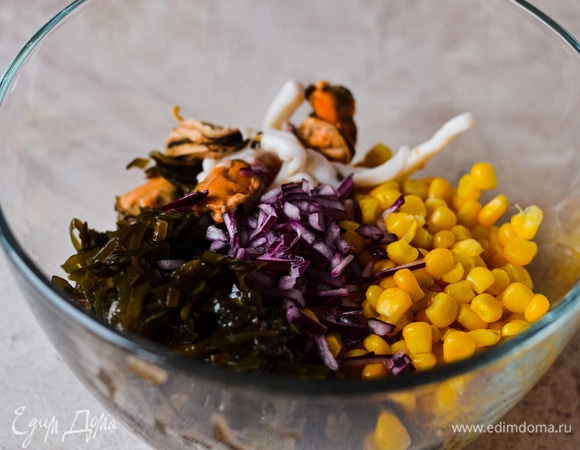 В миске смешиваем капусту, морской коктейль (без жидкости), кукурузу и мелко порубленный лук.