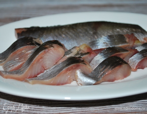 Для салата сельдь разделайте, удалите внутренности, очистите от пленки и костей. Рыбу нарежьте на тонкие кусочки.