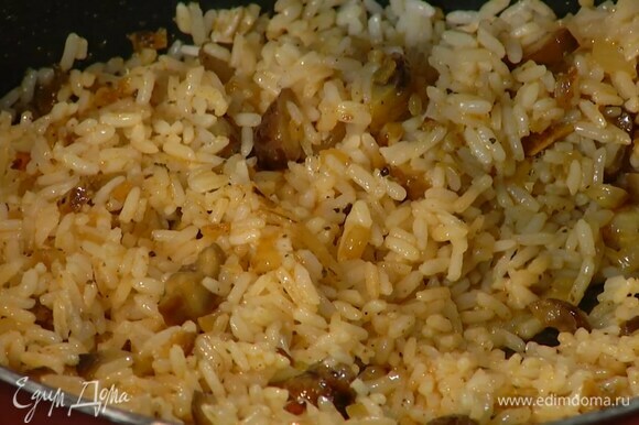 Добавить в сковороду отваренный рис, влить горячий бульон, все посолить и, помешивая, прогревать, пока бульон не выпарится.