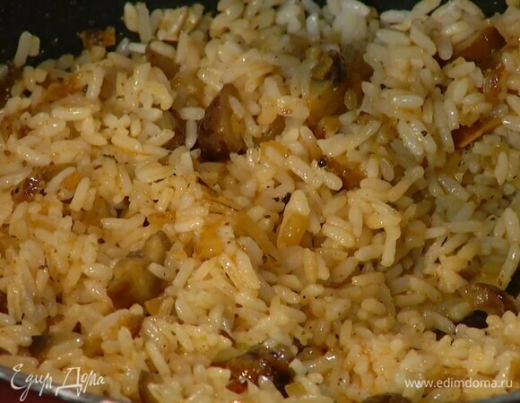 Добавить в сковороду отваренный рис, влить горячий бульон, все посолить и, помешивая, прогревать, пока бульон не выпарится.