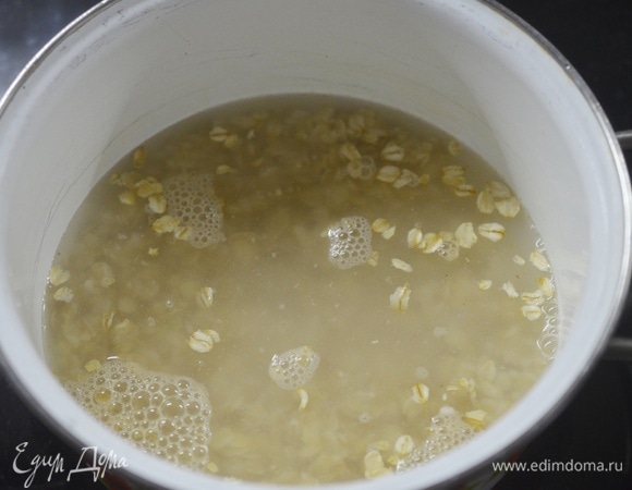 В посуду для варки каши добавьте овсяные хлопья, влейте воду.