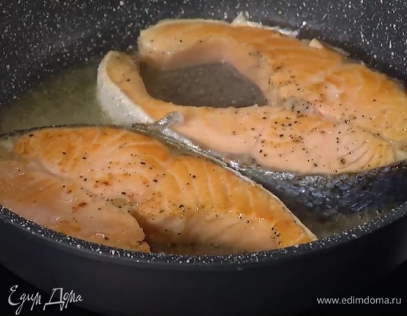 Стейки лосося посолить и поперчить с двух сторон, полить оливковым маслом и обжарить на сухой сковороде с одной стороны, затем перевернуть, накрыть крышкой, обжарить с другой стороны и снова перевернуть.