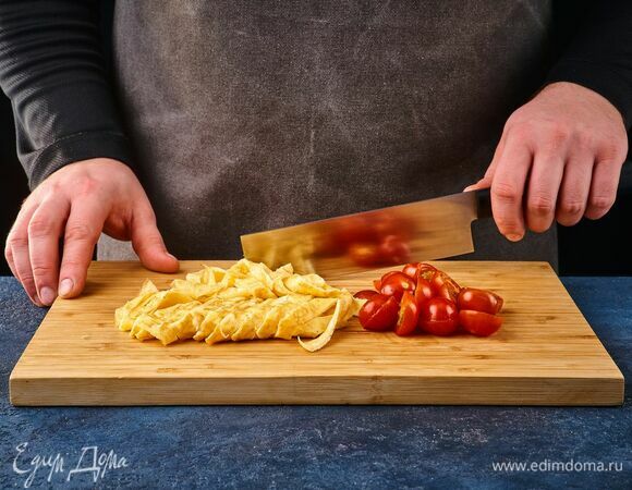 Остудите омлет и нарежьте соломкой. Помидоры черри разрежьте пополам.