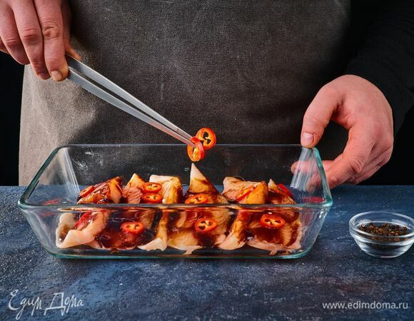 Добавьте нарезанный кружочками перец чили и черный перец по вкусу. Накройте рыбу пленкой и поставьте мариноваться на 2 часа.