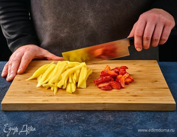Клубнику нарежьте средними дольками, а манго — слайсами. 