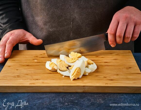 Вареные яйца очистите от скорлупы, нарежьте на четвертинки.