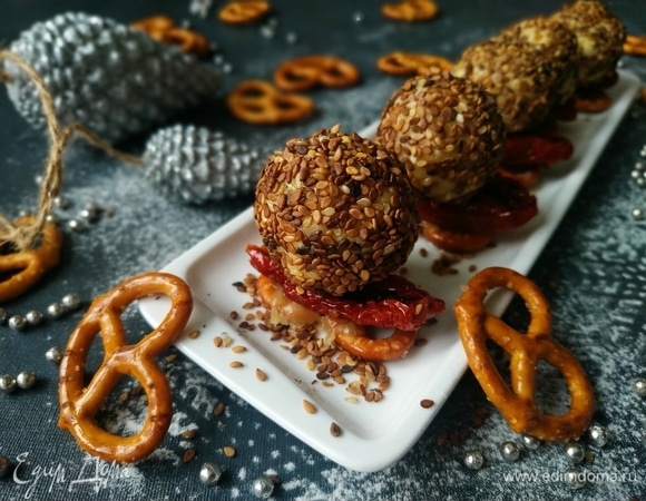 Запеченные крендельки с сыром выложите на сервировочное блюдо. Сверху разложите дольки вяленых томатов, на томаты —сырные шарики. Подавайте к столу. Приятного аппетита и счастливых вам новогодних праздников.