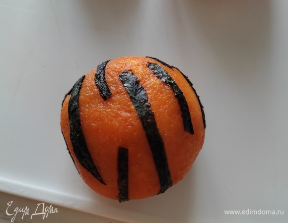 Небольшие кусочки в хоатичном порядке приклеить на нашу оранжевую заготовку, имитируя рисунок шкуры тигра. Чтобы лучше кусочки прилипали к поверхности, смочите их немного водой. Петелька у шариков сделана из половины маслины и кусочка пера зеленого лука. Из указанных ингредиентов получается 3 шарика диаметром около 6 см.