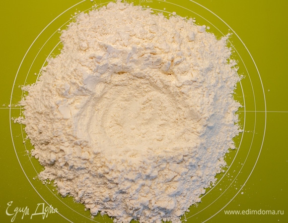 Муку просеять на рабочую поверхность, сделать углубление.