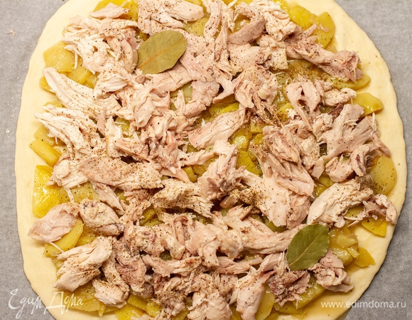 Ту часть, что больше, использовать для нижнего слоя. Раскатать и перенести на пергамент, выложить картофель с луком и курицу. Посолить и поперчить.