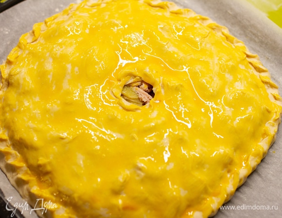 Вторую часть теста раскатать и накрыть пирог, края залепить, в середине пирога сделать отверстие. Смазать яичным желтком. Выпекать при 180°C. Когда пирог подрумянится, влить в отверстие 100 мл горячего куриного бульона. Печь еще примерно 10 минут. Приятного аппетита!