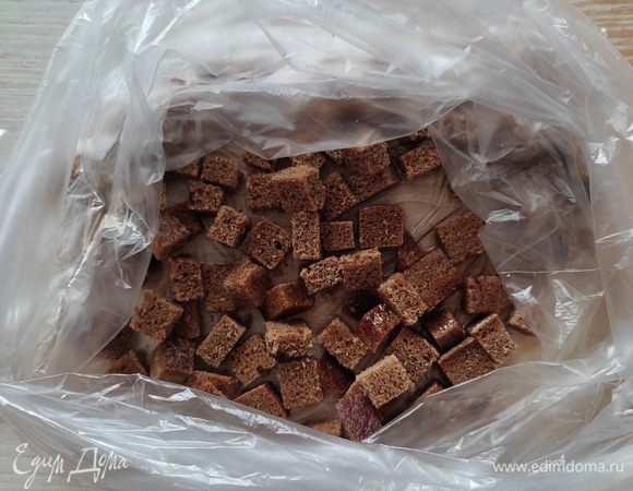 Приготовим сухарики. 2–3 ломтика ржаного хлеба нарезать мелким кубиком, сложить в пакет, туда же добавить растительное масло, закрыть пакет и хорошо потрясти, чтобы масло обволокло каждый кубик. Выложить на противень, запечь в духовке при 180°C 3–4 минуты до хруста.