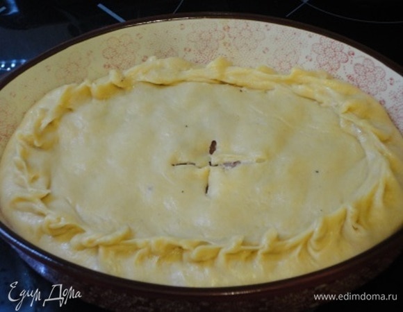 Форму для запекания с высокими бортиками смажьте маслом. Тесто разделите на 2 части. Большую раскатайте, выложите на дно посуды и сформируйте бортики. Выложите на основу начинку, а небольшой кусочек теста раскатайте и накройте им начинку. Защипните края, сделайте сверху отверстие.