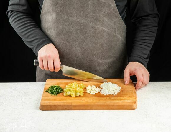 Лук и чеснок почистите и мелко нарежьте. Петрушку мелко порубите. Виноград разрежьте на половинки.