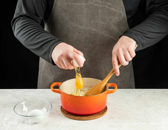 Снимите сотейник с огня и медленно перемешивайте тесто около 3 минут, пока оно не остынет. Добавьте яйца по одному, перемешайте.