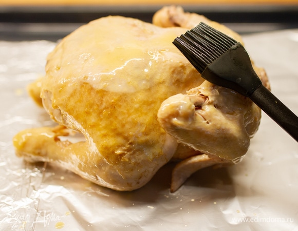Курицу выложить на тарелку, дать немного остыть, затем переложить в глубокий противень, застеленный пищевой фольгой. Сливочное масло (20 г) растопить и с помощью кисточки смазать тушку. Посолить и поместить в духовку, нагретую до 190°C, на 20 минут.