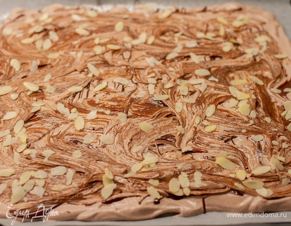 Выложить белковую массу на противень, застеленный пергаментной бумагой, и разровнять. Шоколад растопить и вылить сверху на белки, провести лопаткой, образуя мраморный рисунок. Посыпать миндальными лепестками. Выпекать при 130°C 1 час.