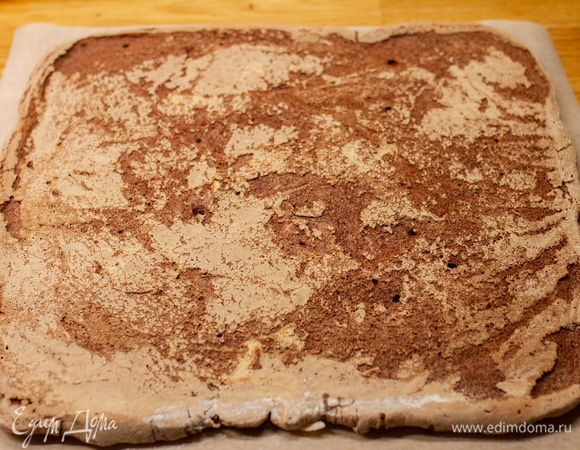 На меренговый корж положить лист пергамента и аккуратно перевернуть. Остудить в течение 3–5 минут.