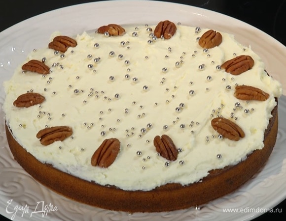 Остывший пирог смазать кремом, посыпать кондитерскими украшениями и выложить по кругу орехи пекан.