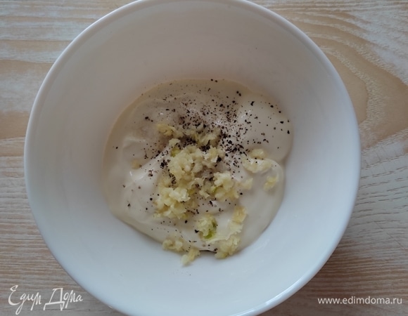 Для соуса в сметану выдавливаем чеснок с помощью пресса, добавляем по вкусу черный молотый перец, соль, перемешиваем до однородности.