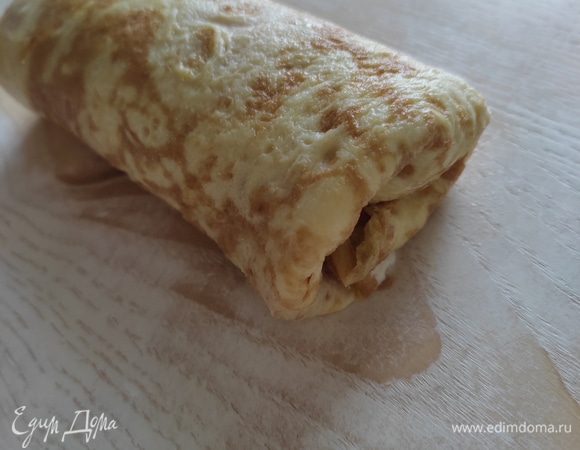 Сворачиваем блинчик в рулет, подгибая боковые края внутрь, чтобы при запекании не вытекла начинка. Аналогично заворачиваем еще 3 блинчика.