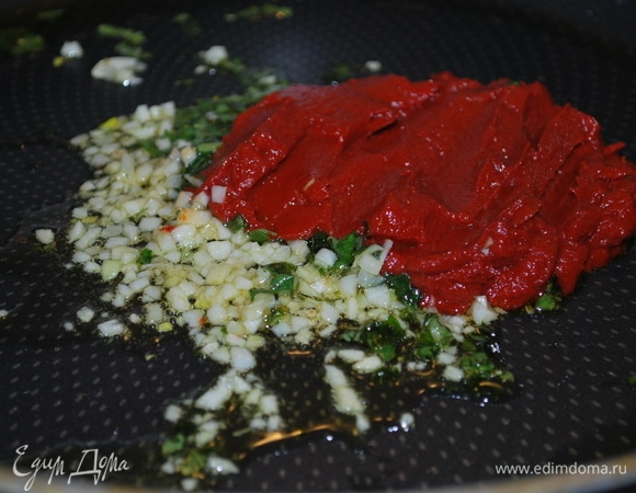 Листья базилика вымойте и нарежьте на тонкие полоски, чеснок очистите и мелко порубите. Сковороду с толстым дном разогрейте, налейте оливковое масло. Добавьте базилик, чеснок, томатную пасту, перемешайте и обжарьте все в течение 2–3 минут.