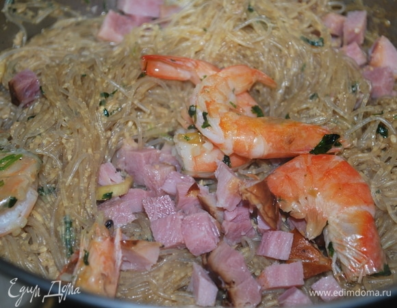 Как только фунчоза станет мягкой, добавьте нарезанный на мелкие кубики бекон, креветки и кунжутное масло. Перемешайте, прогрейте все вместе 1–2 минуты, накройте сотейник крышкой и снимите с огня.