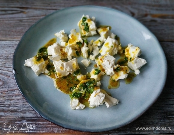 Возьмите тарелку для салата, руками разломайте на небольшие кусочки сыр, полейте заправкой.