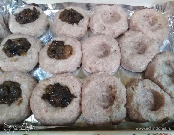 Форму застелить фольгой. Слепить из фарша котлеты и выложить на фольгу. В середине каждой сделать углубление, выложить начинку из грибов.