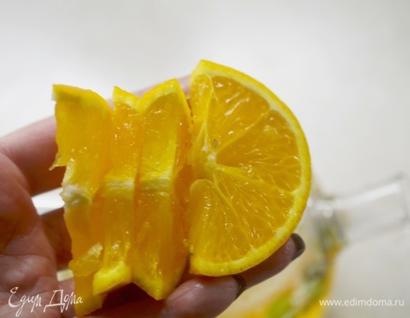 Апельсин помойте, нарежьте на дольки. Добавьте в посуду для заваривания.