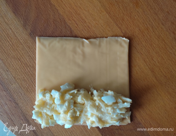 На пластинку сыра выкладываем на один край начинку и аккуратно сворачиваем в трубочку. Начинки должно быть столько, чтобы пластинка соединилась краями.