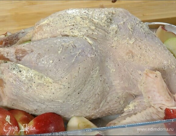 Тушку индейки вымыть, обсушить, натереть пряным маслом снаружи и внутри и выложить в форму для запекания. В брюшко поместить как можно больше яблок, остальные разложить вокруг индейки.