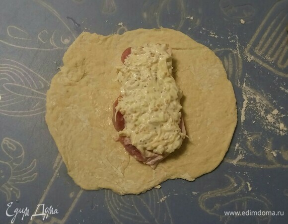 Припылить рабочую поверхность блинной мукой и раскатать одну часть теста. Положить в центр кусок мяса, смазать его половиной смести майонеза и горчицы, посыпать частью нарезанного репчатого лука и натертого сыра. Обернуть мясо тестом. Затем так же поступить со второй частью теста и мяса.
