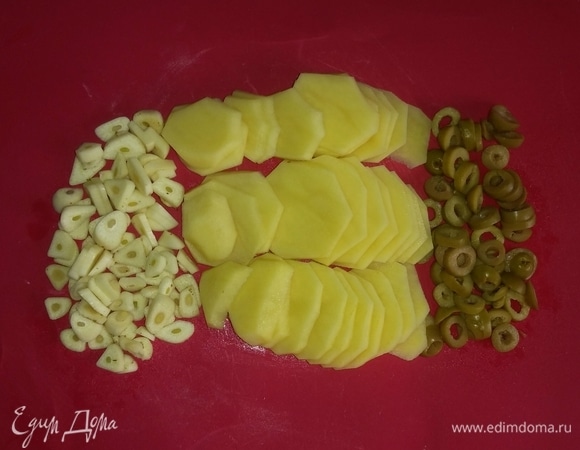 Картошку и чеснок нужно предварительно почистить и помыть. Затем картошку, зубчики чеснока и оливки нарезать тонкими кружочками.