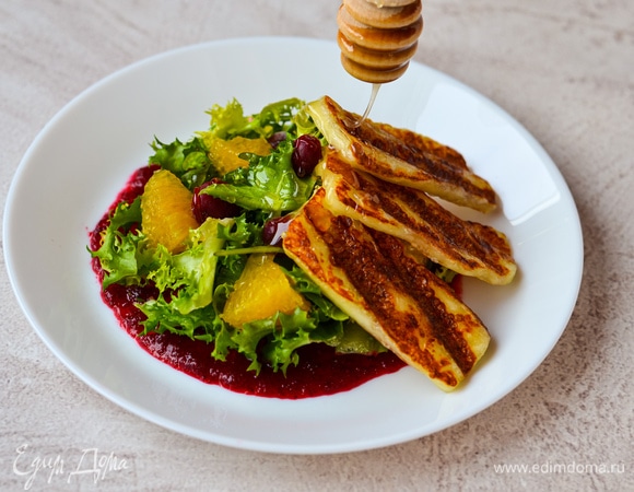 Выложить апельсины, клюкву и сыр. Полить медом.