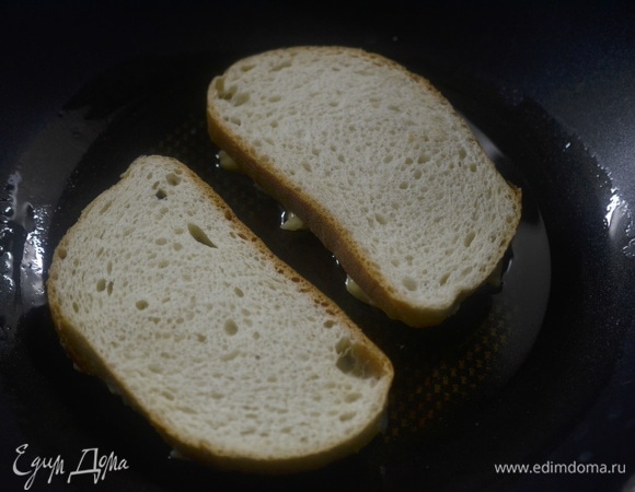 В сковороде разогрейте масло, выложите бутерброды начинкой вниз.