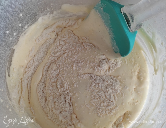 Муку просеиваем с разрыхлителем и понемногу вмешиваем в тесто с помощью лопатки.