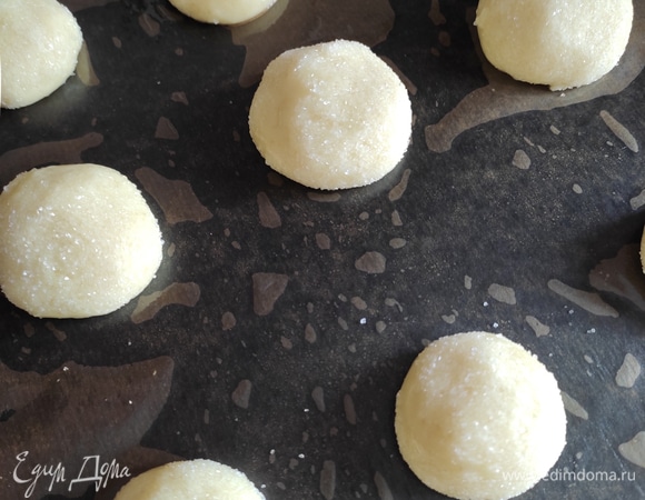 Выкладываем шарики на расстоянии друг от друга на противень, предварительно застеленный пергаментом. Если у вас пергамент не силиконизированный, смажьте его растительным маслом с помощью кисти. Также можно использовать тефлоновый коврик.