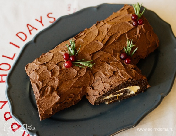 Затем край рулета обрезать наискосок с одной стороны, чтобы сделать «сучок». Приложить отрезанную часть к боку рулет. Затем мазками нанести шоколадный крем, имитируя кору дерева. Украсить ягодами клюквы и веточками розмарина. Убрать в холодильник на 2 часа. Приятного аппетита!