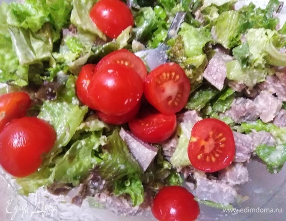 Нарезать томаты черри и соединить с салатом.