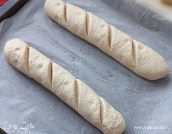 Выкладываем на противень с бумагой и делаем на батонах надрезы.