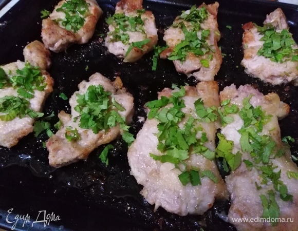 Достать готовые отбивные. Посыпать сушеным чесноком и свежей кинзой.